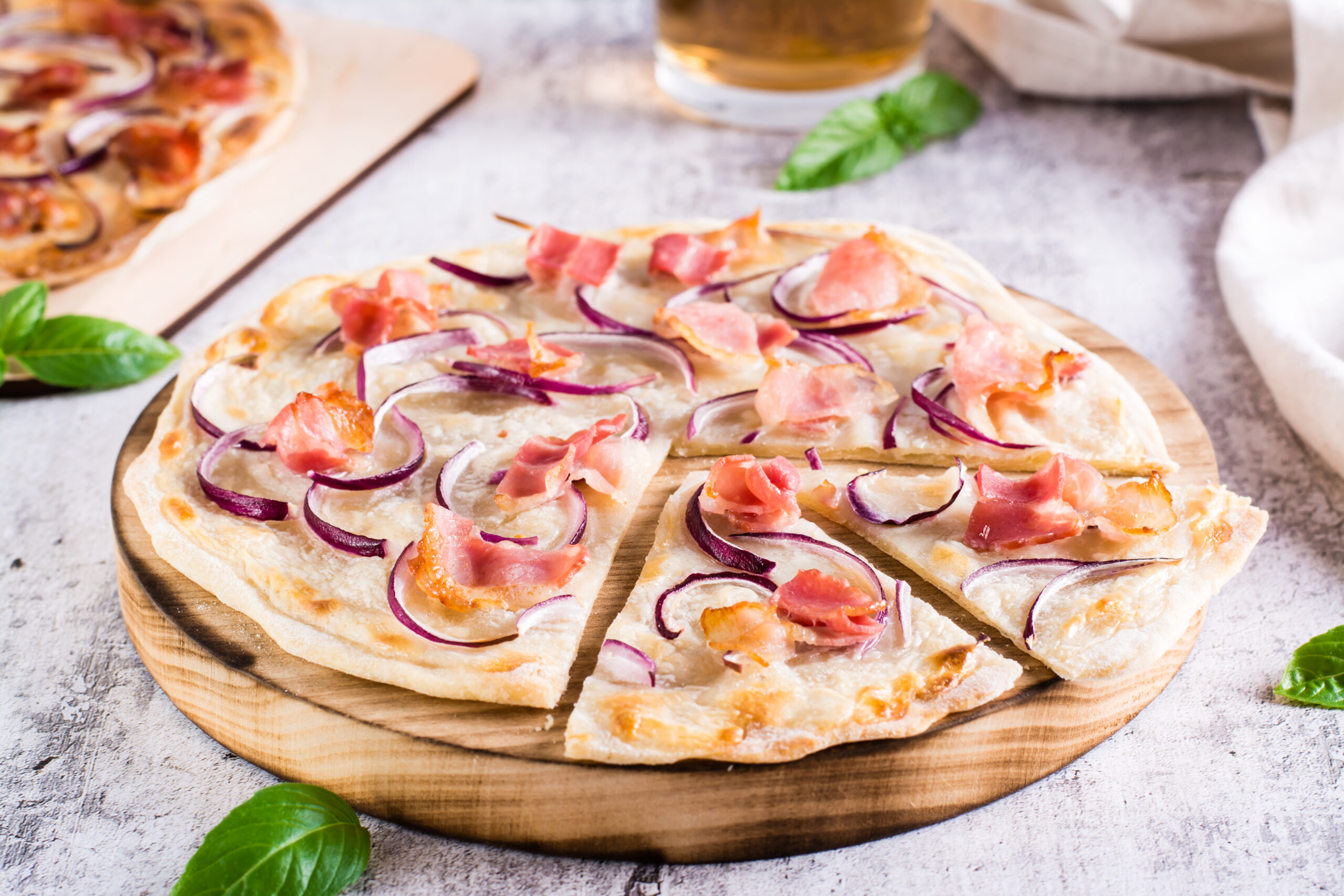 French tarte flammkuchen with cream cheese, onion and bacon on a